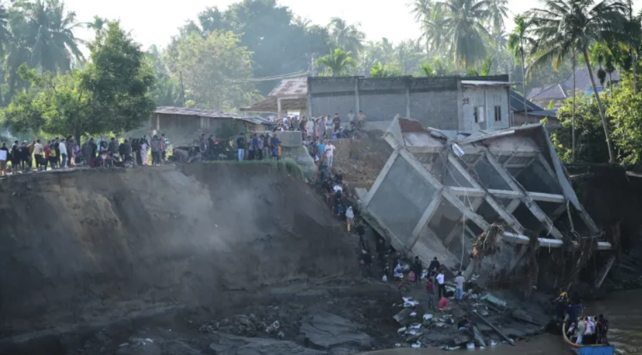 People walk down the embankment of a river to take a boat ride across, after a bridge nearby collapsed during a flood in Bireun, Aceh province, Indonesia on November 29, 2025 (PC: AP)