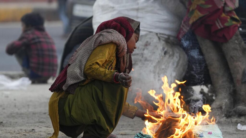 A girl warms herself by a bonfire on a cold winter morning in New Delhi as temperatures dropped to one of the lowest levels of the season, according to the India Meteorological Department. (Photo Credits: PTI)